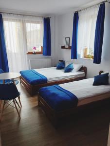 two beds in a room with blue curtains and a table at Willa Czyrna przy Gondoli in Szczyrk