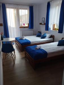 two beds in a room with blue curtains and a table at Willa Czyrna przy Gondoli in Szczyrk
