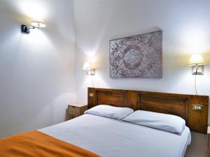 a bedroom with a bed with white sheets and two lights at Charming apartment in Mantignana with shared pool in Mantignana