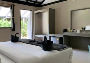 Un dormitorio con una cama con zapatos negros. en Siam Flora Resort Koh Lanta en Ko Lanta