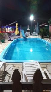 una gran piscina por la noche con 2 tumbonas en Pousada Vila D' Itália, en Penha