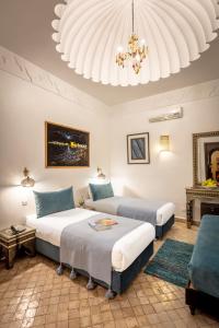 a bedroom with two beds and a chandelier at Riad & Spa Bahia Salam in Marrakech