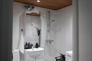 a white bathroom with a shower and a sink at Tyylikäs hyvin varusteltu asunto. Oma autopaikka. in Salo