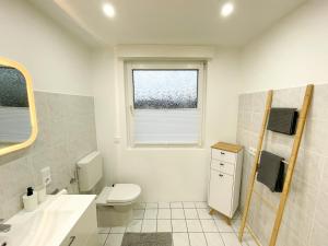 a bathroom with a toilet and a sink and a window at Ferienwohnung Schönes Maifeld in Polch
