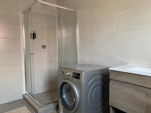 a washing machine in a bathroom with a shower at Lion House, 3 bedroom House next to Pilanesberg and Sun City in Mogwase