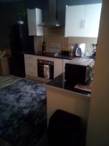 eine Küche mit weißen Schränken und einer schwarzen Arbeitsplatte in der Unterkunft Oak 2 Bed Apartment (Plus Sofa Bed - Sleeps 6) in Blackpool