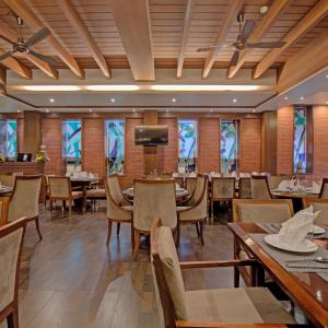 a restaurant with tables and chairs and a flat screen tv at Godwin Goa in Candolim