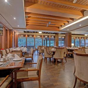 a dining room with tables and chairs and windows at Godwin Goa in Candolim