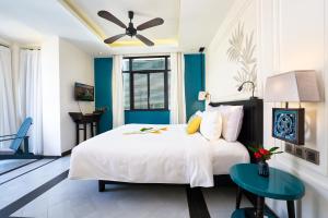 a bedroom with a white bed and a blue wall at Maison Vy Hotel in Hoi An