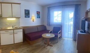 ein Wohnzimmer mit einem Sofa und einem Tisch sowie eine Küche in der Unterkunft Das Weber in Sankt Jakob in Defereggen