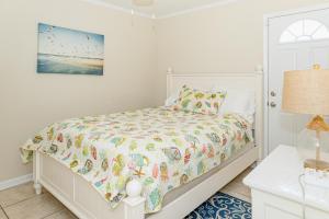 a white bedroom with a bed and a lamp at Seaview Duplex 6 & 7 in Kure Beach
