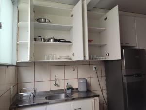 cocina con armarios blancos, fregadero y nevera en Apartamento 2 quartos Setor Sul, en Goiânia