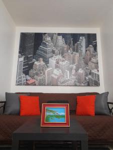 Cozy Apartment across the San Juan Airport في سان خوان: غرفة معيشة مع أريكة مع لوحة على الحائط