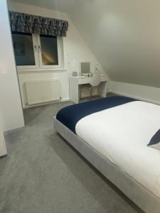 a white bedroom with a bed and a desk at Alma Villa in Falkirk