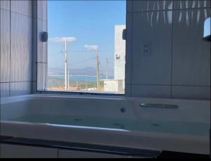 a bath tub in a bathroom with a window at Casa com piscina Capitólio in Capitólio +7 photos