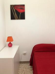 サン・ヴィート・ロ・カーポにあるResidence Arcobalenoのベッドルーム1室(赤いベッド1台、ランプ付きテーブル付)