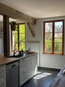 uma cozinha com um lavatório e duas janelas em Maison de vacances dans un village de charme 
