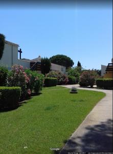 een tuin met groen gras en bloemen en een stoep bij Tennis Village in Cap d'Agde
