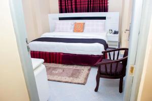 ein Schlafzimmer mit einem Bett und einem Stuhl darin in der Unterkunft Hotel Kingdom Appartments in Mwanza