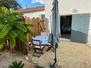 a umbrella and a chair in a yard at La cabane de Lily - T2 classé 3 étoiles in Rochefort