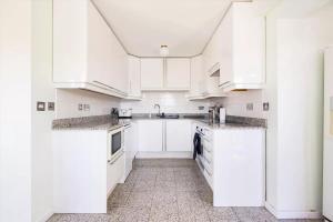 a white kitchen with white cabinets and appliances at City Riverview Apartment with Parking in London