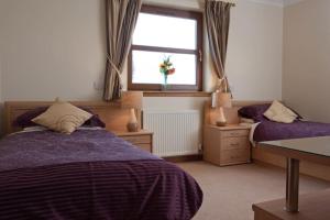 1 dormitorio con 2 camas y ventana en Ardmore luxury self catering cottage, en Broadford