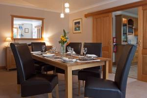 a dining room table with black chairs and a wooden table with wine glasses at Ardmore luxury self catering cottage in Broadford