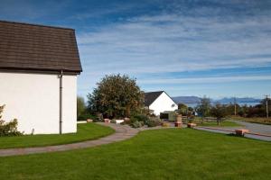 una casa con un patio de césped al lado de un edificio en Ardmore luxury self catering cottage, en Broadford