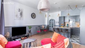 a living room with a red couch and a kitchen at Cauquilha SPACIEUX APPARTEMENT BOURGEOIS EN CENTRE VILLE in Béziers