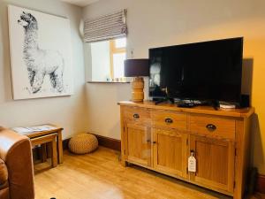 a living room with a television on a wooden entertainment center at Rustic Retreats: Owslow Cottage with hot tub & Alpaca Walking Experiences in Carsington