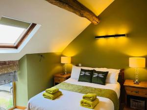 a bedroom with a bed with two yellow towels on it at Rustic Retreats: Owslow Cottage with hot tub & Alpaca Walking Experiences in Carsington
