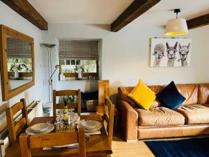 a living room with a couch and a table at Rustic Retreats: Owslow Cottage with hot tub & Alpaca Walking Experiences in Carsington