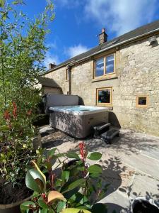 a large bed sitting outside of a house at Rustic Retreats: Owslow Cottage with hot tub & Alpaca Walking Experiences in Carsington
