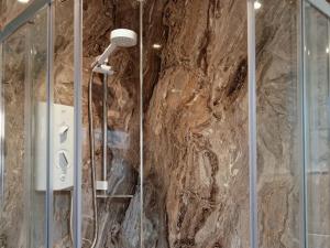 y baño con ducha y pared de piedra. en Waves And Wolds, en Sewerby