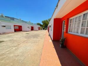 un estacionamiento vacío junto a un edificio rojo en Apart Alto Parana en Paso de la Patria