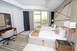 a hotel room with two beds and a window at Seafront Luxury Suites Jeddah Corniche in Jeddah