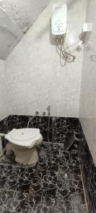 La salle de bains est pourvue de toilettes et d'un téléphone mural. dans l'établissement REVA ROOM'S, à Rājpīpla