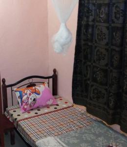 una piccola camera da letto con letto, cuscino e tenda di Colours Club and Spa a Kigali
