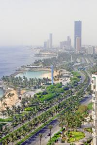 an aerial view of a city with palm trees and the ocean at Seafront Luxury Suites Jeddah Corniche in Jeddah