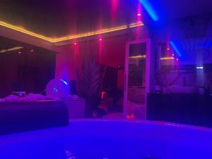 un salon avec des lumières violettes et bleues dans l'établissement L'Aurore suite de charme, clim jacuzzi, sauna, piscine chauffée cuisine..., à Carpentras