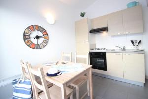 a kitchen with a table and a clock on the wall at Le Clos des Flots - La Dune in La Flotte