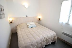 a small bedroom with a white bed with two lamps at Le Clos des Flots - La Dune in La Flotte