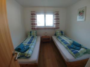 two twin beds in a room with a window at Haus am See in Tarasp
