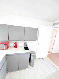 Spacious Two Bedroom flat في Hither Green: مطبخ فيه دواليب بيضاء واجهزة حمراء