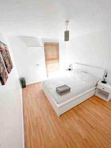 a white bedroom with a bed and a wooden floor at Spacious Two Bedroom flat in Hither Green