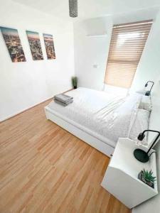 a white bedroom with a bed and a desk at Spacious Two Bedroom flat in Hither Green