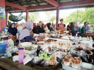 un grupo de personas sentadas alrededor de una mesa con comida en PCB PURPLE GUEST HOUSE, en Kota Bharu