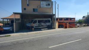 una persona de pie detrás de una puerta en un lado de un edificio en Pousada GEF Aparecida, en Aparecida