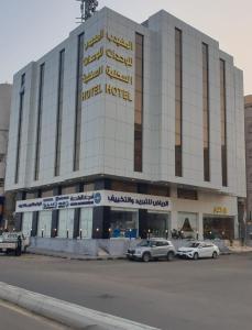 un grand bâtiment avec des voitures garées devant lui dans l'établissement المهيدب للوحدات السكنيه - البوادي, à Djeddah