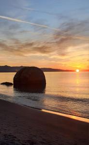 a sunset over a beach with a large rock in the water at Trilocale Margine Rosso in Quartu SantʼElena